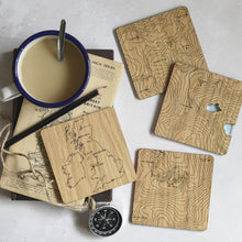 Load image into Gallery viewer, Wooden coasters featuring maps of the three national peaks and a map of the UK showing the peaks' location. A blue tinted acrylic is set into the Snowdon coaster to depict the tarns.