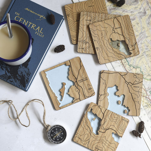 Wooden coasters featuring maps from The Lake District. A blue tinted acrylic is set into the coasters to depict the lakes and tarns.